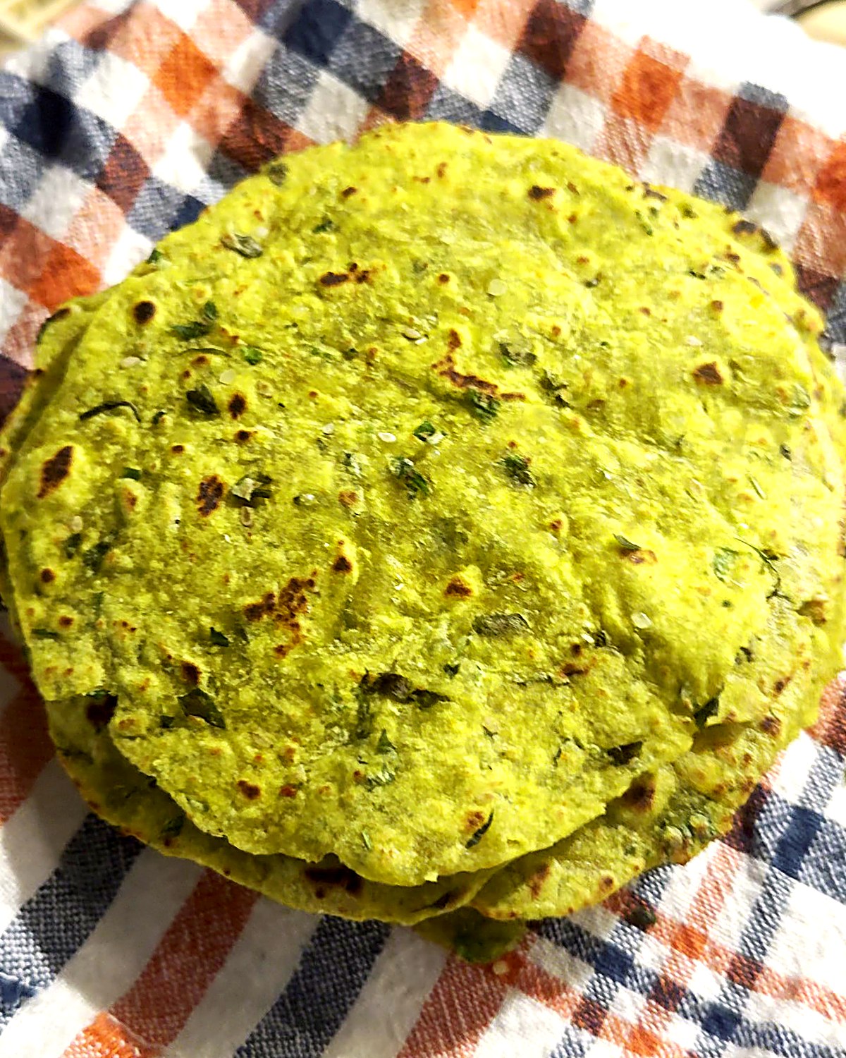 Stack of soft high protein methi thepla on a checked cloth